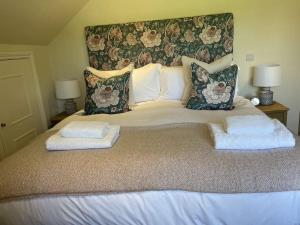 - un grand lit avec 2 oreillers et des serviettes dans l'établissement Cottage 2, Northbrook Park, Farnham-up to 6 adults, à Farnham