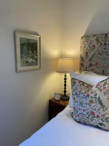 Dormitorio con cama con almohada y lámpara en Cottage 2, Northbrook Park, Farnham-up to 6 adults en Farnham