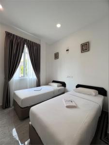 a hotel room with two beds and a window at Srg Indira Hotel in Gelang Patah