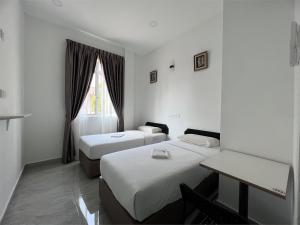 a room with two beds and a table and a window at Srg Indira Hotel in Gelang Patah