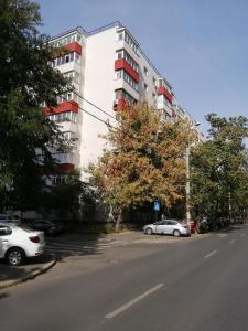 a white apartment building with cars parked in a parking lot at Askade Residence Self Check-in in Bucharest