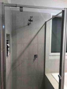Happy House في Melton South: دش في حمام مع باب زجاجي