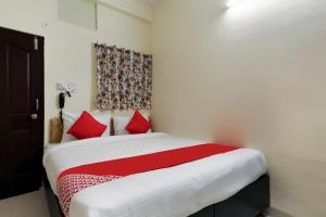 Hotel Aashirwad في إندوري: غرفة نوم بسرير كبير ومخدات حمراء