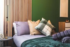 a bed with pillows on it with a green wall at Dreamy Derby City Apartment Free Wi-Fi & Parking in Derby