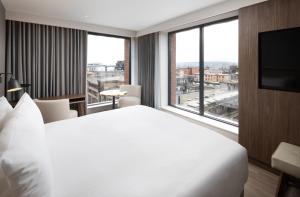 AC Hotel by Marriott Glasgow في غلاسكو: غرفة فندقية بسرير كبير ونافذة كبيرة