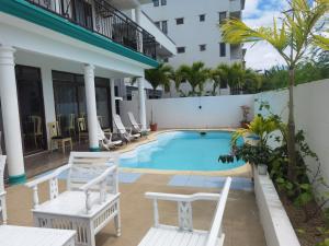 a pool in the courtyard of a hotel with chairs at Grand Bay Apartments in Grand Baie