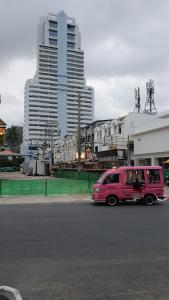 una furgoneta rosa estacionada al lado de una calle en PATONG TOWER FAMILY WELCOME by PTA en Patong Beach