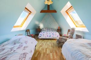 a attic bedroom with two beds and two windows at Maison pêcheur à 300m de la plage in Pleubian