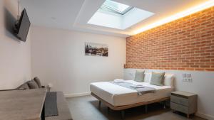 a bedroom with a bed and a brick wall at Apartamentos Dolium in Seville