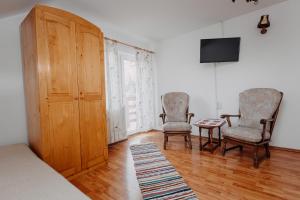 sypialnia z 2 krzesłami, telewizorem i stołem w obiekcie Kaffai Panzio w mieście Izvoru Mureşului