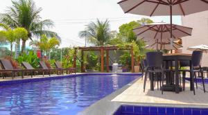 a pool with chairs and umbrellas and a table with an umbrella at Altiplano Hotel in João Pessoa