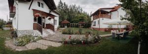 a house with a garden with flowers and an umbrella at Kaffai Panzio in Izvoru Mureşului
