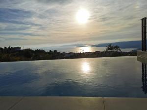 a large swimming pool with the sun in the sky at Sunset Luxury Villa in Akritokhórion