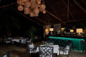 a dining room with tables and chairs and chandeliers at Saffron Garden Malindi in Malindi