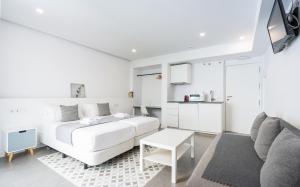 a white bedroom with a white bed and a couch at Dolium Apartments in Seville