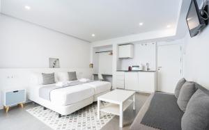a white bedroom with a white bed and a couch at Apartamentos Dolium in Seville