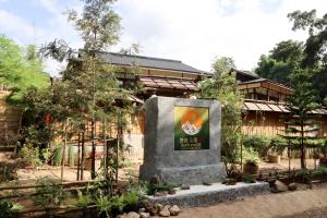 un monument dans un jardin en face d'un bâtiment dans l'établissement เรียวกัง ยามะโฮชิ Ryokan Yamahoshi เชียงใหม่, à Chiang Dao