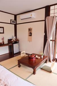 - un salon avec une table basse et un bureau dans l'établissement เรียวกัง ยามะโฮชิ Ryokan Yamahoshi เชียงใหม่, à Chiang Dao
