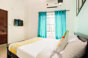 Schlafzimmer mit einem Bett und einem Fenster mit blauen Vorhängen in der Unterkunft OYO Home KC Arcade in Kochi