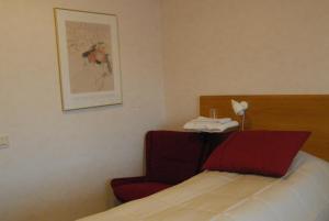 una camera d'albergo con letto e sedia rossa di Katrinebergs Folkhögskola B&B a Vessigebro