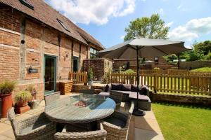 un patio con una mesa y una sombrilla en The Byre - Beautiful Contemporary Barn - Hot Tub, en Bridgnorth