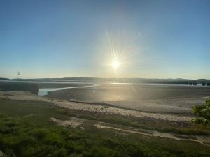 a sun setting over a river with a beach at Seaside & Lake District retreat in Arnside