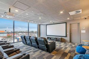 um quarto amplo com cadeiras e um ecrã de projecção em Adelaide Skyline Serenity: Gym, Pool & views em Adelaide