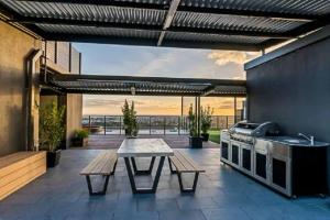 um pátio com uma mesa e uma cozinha com vista em Adelaide Skyline Serenity: Gym, Pool & views em Adelaide