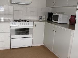 a white kitchen with a stove and a microwave at Öje Vandrarhem & Turistgård in Östra Öje