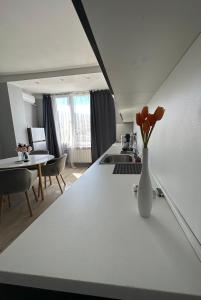 Rose's apartment , self check-in, close to metro في صوفيا: مطبخ أبيض مع إناء من الزهور على منضدة