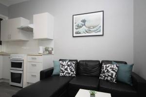 een woonkamer met een zwarte bank en een keuken bij Central Beach Apartment & Free Parking in Blackpool