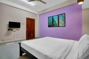 a bedroom with a white bed and a purple wall at Collection O Lala Homes in Alwaye