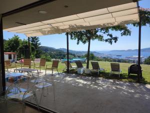 d'une terrasse avec des chaises et des tables et une vue sur l'eau. dans l'établissement Casa con vistas al mar en Pontevedra, à Pontevedra