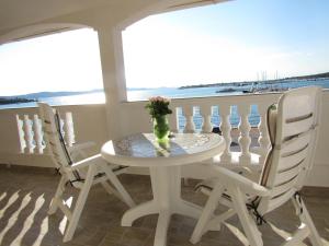 a table with two chairs and a vase of flowers on a balcony at Apartments Renjak in Sukošan