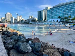 Condado Beachfront Tantra Apartment في سان خوان: شاطئ فيه ناس في المياه والمباني