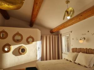Schlafzimmer mit einem Bett, einem Fenster und Holzbalken in der Unterkunft Maison de famille in Bouillargues