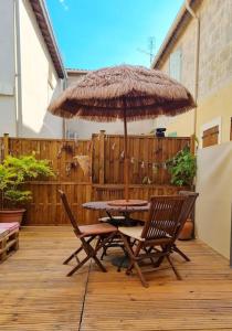 einen Tisch und Stühle unter einem Sonnenschirm auf einer Terrasse in der Unterkunft Maison de famille in Bouillargues