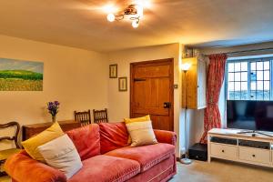 a living room with a red couch and a television at Finest Retreats - Clematis Cottage in Stogursey