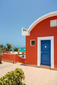 a red building with a blue door and the ocean at La Madrague-Surf Beach Sea in Dakar