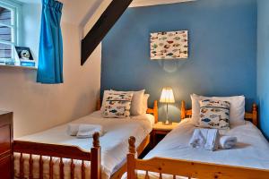 two twin beds in a room with blue walls at Finest Retreats - Clematis Cottage in Stogursey