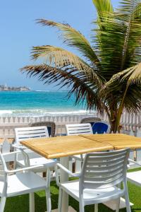 a wooden table and chairs next to the beach at La Madrague-Surf Beach Sea in Dakar