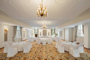 ein Ballsaal mit weißen Tischen und Stühlen und einem Kronleuchter in der Unterkunft WelcomHeritage Santa Roza Kasauli in Kasauli