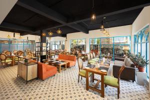 un restaurante con mesas, sillas y ventanas en WelcomHeritage Santa Roza Kasauli en Kasauli