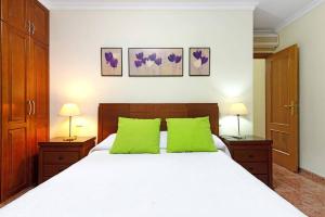 a bedroom with a white bed with two green pillows at Mar y Sol Salinetas in Telde