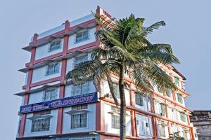 a building with a palm tree in front of it at OYO Flagship Hotel Rainbow in Tezpur