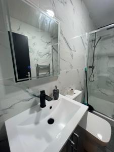 y baño blanco con lavabo y ducha. en NEW Modern Flat! Monthly Discount! Near City Centre, en Cardiff