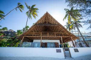 a bamboo building on the beach with palm trees at Beachfront Turtle House ZanzibarHouses in Kiwengwa