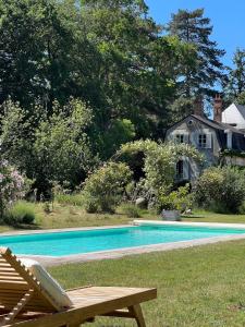 a swimming pool with a bench next to a house at COLIVAULT in Candé-sur-Beuvron