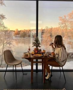 a woman sitting at a table in front of a window at WonderInn Riverside in Årnes