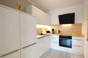 una cocina blanca con armarios y electrodomésticos blancos en Cozy home - Willkommen in Aachen - Boxspringbett - Balkon 